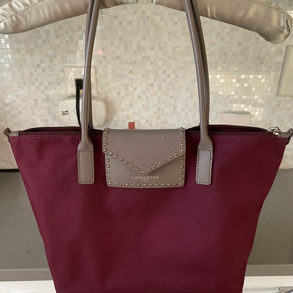 Lancaster Paris Canvas Bag with top zipper, leather handles and flip closure.